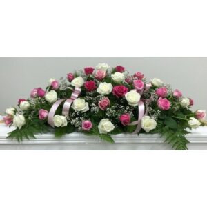 Pink and White Casket Spray featuring white and pink roses, baby's breath, and green foliage with ribbons for sympathy flowers.