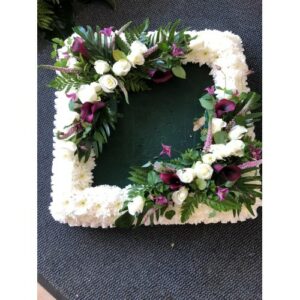 Floral wreath with white flowers and green foliage on a dark background, perfect for a Picture Frame display.