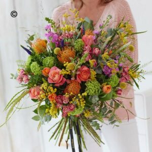 A person holding a Deluxe Spring Boquet of assorted flowers.
