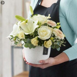 Sentence with product name: Person holding a bouquet of white lilies and roses in a Pot Arrangement.