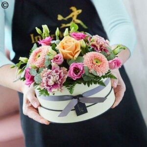 A person holding a Seasonal Hatbox designed to resemble a cake.