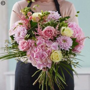 Person holding a large bouquet of Hand Tie Pink Glow and white flowers, hand-tied with care.