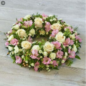 A Flowergram featuring white roses, pink blooms, and green foliage on a light wooden background.