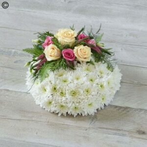 A Traditional Posy featuring white chrysanthemums and pink roses on a wooden surface.