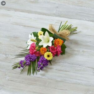 A colorful bouquet of Bright and Bold Tied Sheave flowers arranged on a wooden surface.