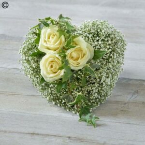 Petite Gypsophila Heart-shaped floral design with white roses and petite Gypsophila on a wooden surface.