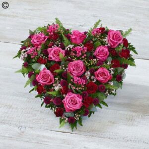 Pink and Red Heart-shaped floral arrangement with pink and red roses and assorted greenery.