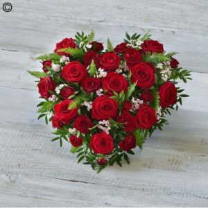 Red Rose Heart-shaped arrangement with greenery on a wooden background.
