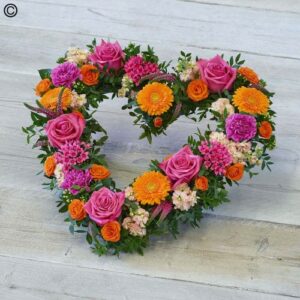 Vivid colorful floral arrangement shaped like an Vivid Open Heart on a light background.