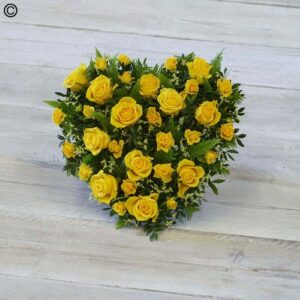 Yellow Rose Heart-shaped arrangement on a wooden surface.