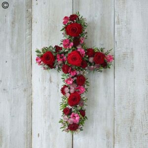 Open floral Red Open Cross arrangement with red roses on a white wooden background.