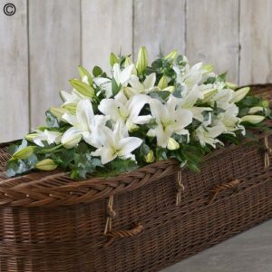 A White Lily Casket Spray arranged in a long wicker basket.