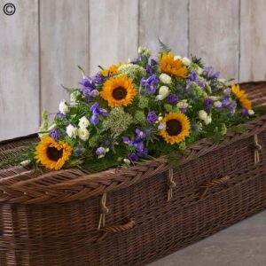 A Sunflower Casket Spray adorned with a floral arrangement of sunflowers and purple blooms.