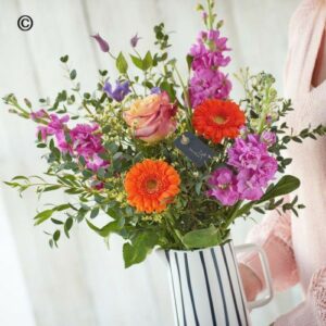 A person holding a bouquet of colorful flowers arranged in a Scented Vivid Vase.