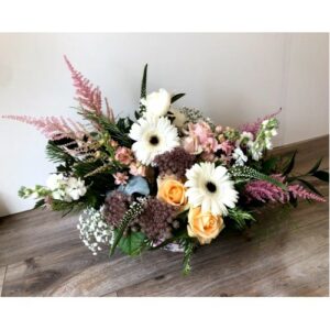 A colorful floral arrangement featuring a mix of white, pink, and peach blossoms with greenery, perfect for Wedding planning, set against a neutral floor background.