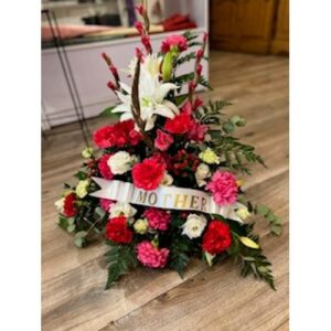 Floral arrangement in a Pink White and Red Basket displayed on a wooden floor.