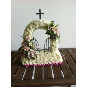 Floral arrangement representing spirituality in the shape of Gates of Heaven on a wooden surface.