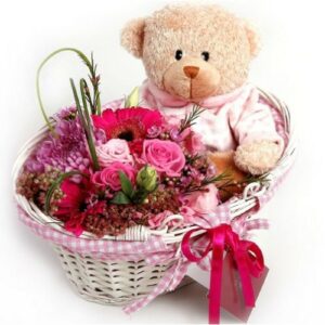 A Basket With Flowers and Bear. New Baby seated in a basket with an assortment of pink flowers and a pink ribbon, perfect for celebrating a new baby.